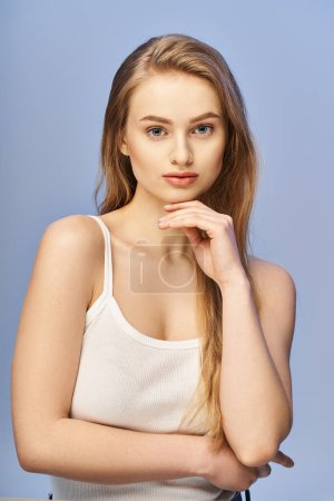 A young blonde woman with long hair strikes a pose in a studio setting for a captivating portrait.