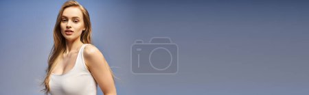 Téléchargez les photos : Une jeune femme blonde au sourire radieux pose gracieusement dans un débardeur blanc, en studio. - en image libre de droit