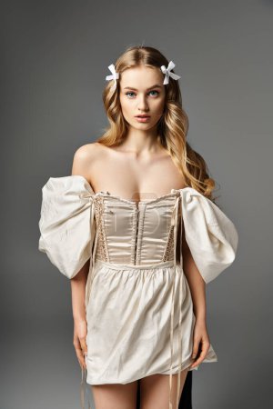 Eine blonde Frau posiert anmutig in einem kurzen Kleid und strahlt in einem Studio-Setting Selbstbewusstsein und Schönheit aus.