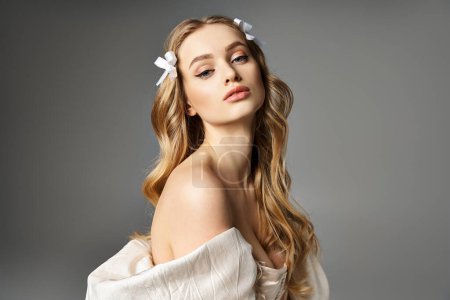 Eine junge blonde Frau steht elegant in einem weißen Kleid, eine einzige Blume steckt in ihrem Haar und strahlt einen Hauch von Anmut und Schönheit aus.