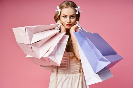 Photo for A young blonde woman striking a confident pose while holding shopping bags in a studio setting. - Royalty Free Image