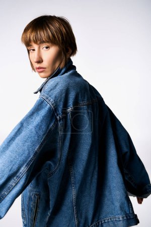 Foto de Una joven de moda que lleva una chaqueta de mezclilla posa con confianza para la cámara de una manera moderna y fresca. - Imagen libre de derechos