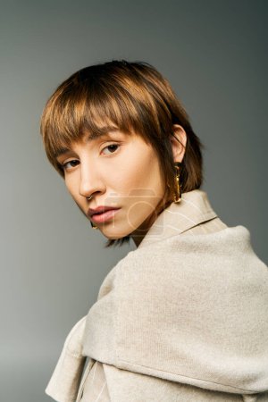 A young woman with a trendy short haircut wearing a fashionable coat in a contemporary studio setting.