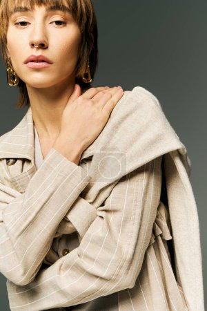 Eine stilvolle junge Frau mit kurzen Haaren trägt einen kuscheligen Pullover in einem Studio-Ambiente, das Eleganz und Komfort ausstrahlt.