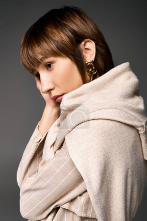 A young woman with short hair elegantly wearing a scarf around her neck in a studio setting.