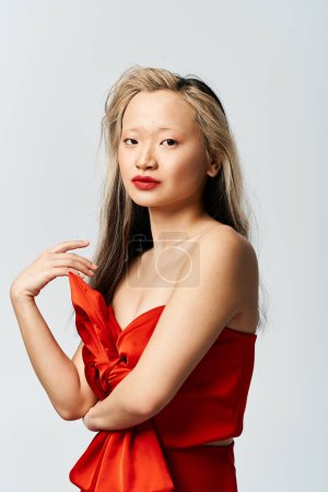 Téléchargez les photos : Une jolie femme asiatique dans une robe rouge vibrante frappant une pose pour une photo. - en image libre de droit