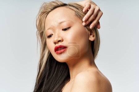 An attractive Asian woman with long hair and red lipstick strikes a pose in vibrant clothes.