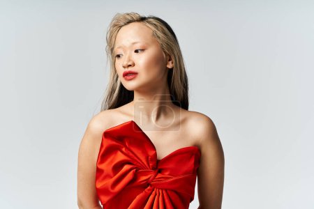 Téléchargez les photos : Vibrante femme asiatique en robe rouge frappant une pose confiante. - en image libre de droit