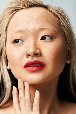 Une femme asiatique glamour avec du rouge à lèvres rouge sur son visage.