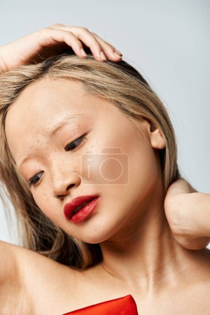 Photo for Active pose of an attractive Asian woman in a red dress lifting her hair. - Royalty Free Image