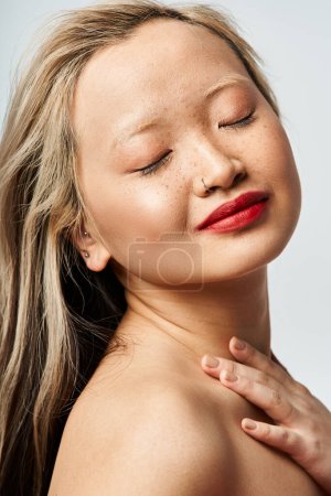 Photo for Asian woman in vibrant clothing, eyes closed, hands on chest - Royalty Free Image