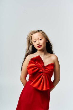 Foto de Asian woman poses gracefully in vibrant red dress. - Imagen libre de derechos