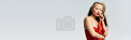 Téléchargez les photos : Attrayante asiatique femme pose gracieusement dans un vibrant rouge robe. - en image libre de droit
