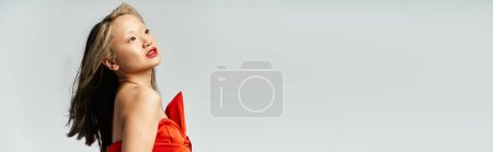 Eine attraktive Asiatin posiert selbstbewusst in einem leuchtend roten Kleid.