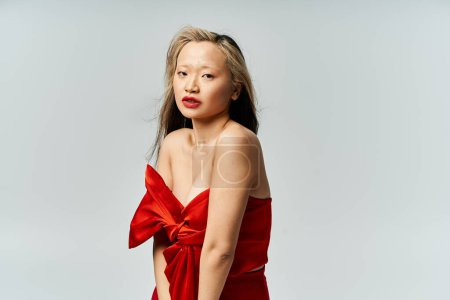 Téléchargez les photos : Une jolie femme asiatique dans une robe rouge vibrante frappant une pose pour une image. - en image libre de droit