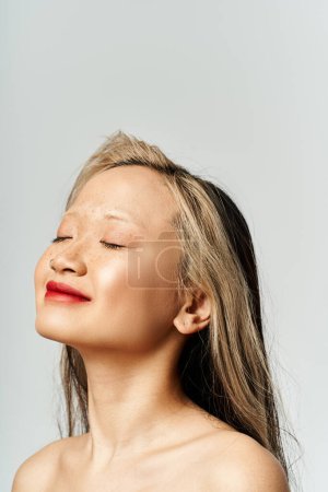 Foto de Una atractiva asiática vestida con ropa vibrante posa con los ojos cerrados, encarnando una sensación de tranquilidad y movimiento. - Imagen libre de derechos