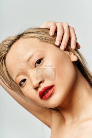 Una atractiva mujer asiática vistiendo ropa vibrante, haciendo alarde de lápiz labial rojo en su cara.
