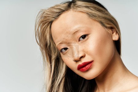 Foto de Una atractiva mujer asiática con el pelo largo y lápiz labial rojo golpeando una pose. - Imagen libre de derechos
