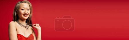 Téléchargez les photos : Une jolie femme asiatique dans une robe rouge vibrante frappant une pose pour une photographie. - en image libre de droit