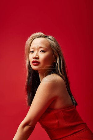 Téléchargez les photos : Une femme asiatique captivante frappe une pose dans une robe rouge vibrante. - en image libre de droit
