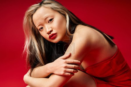 A vibrant Asian woman in a red dress striking a pose for a photo.