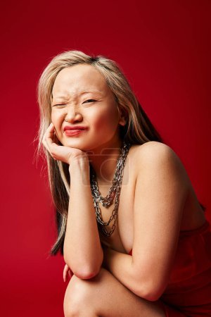 Téléchargez les photos : Femme asiatique dans une robe rouge frappante frappe une pose pour la caméra. - en image libre de droit