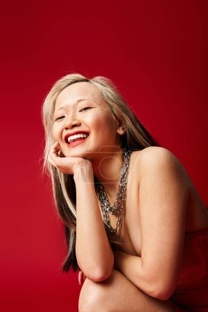 An attractive Asian woman in vibrant clothing smiles brightly.