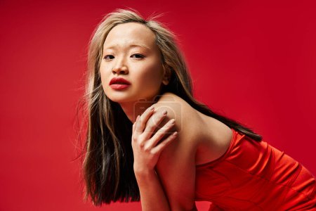 Téléchargez les photos : Une femme asiatique dynamique dans une robe rouge vibrante frappe une pose. - en image libre de droit
