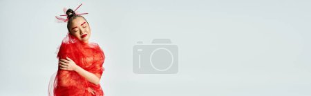 Photo for An attractive Asian woman in a red dress poses with a veil. - Royalty Free Image
