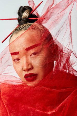Foto de Mujer asiática exuda encanto con maquillaje rojo y un velo cubierto. - Imagen libre de derechos