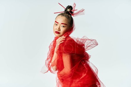 Mujer asiática pose llamativa en vestido rojo impresionante y velo a juego.