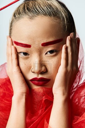 Asian woman with red makeup, hands to face.