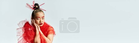 Téléchargez les photos : Une femme asiatique vibrante dans une robe rouge frappante posant avec un voile rouge. - en image libre de droit