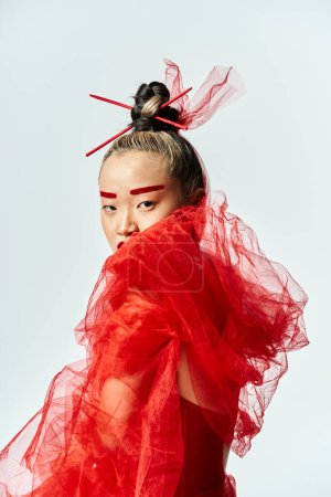 Photo for Asian woman in vibrant red dress and veil posing elegantly. - Royalty Free Image