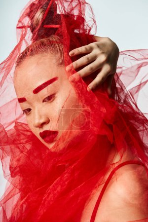 Foto de Mujer asiática en vestido rojo posa con velo que fluye. - Imagen libre de derechos