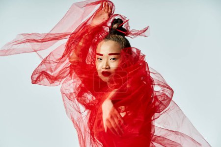 Téléchargez les photos : Une jolie femme asiatique frappe une pose dans une robe rouge vibrante. - en image libre de droit