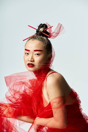Téléchargez les photos : Femme asiatique vibrante en robe rouge avec voile pose en toute confiance. - en image libre de droit