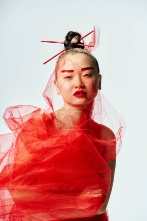 Lebendige Asiatin posiert in einem roten Kleid mit Schleier auf dem Kopf.