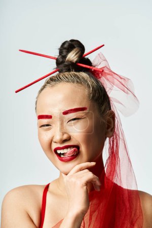 Una atractiva mujer asiática con llamativo maquillaje rojo y un vibrante velo rojo adornando su cabeza.