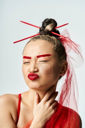 Foto de Mujer asiática adornada con maquillaje rojo y un velo, exudando elegancia y misterio. - Imagen libre de derechos
