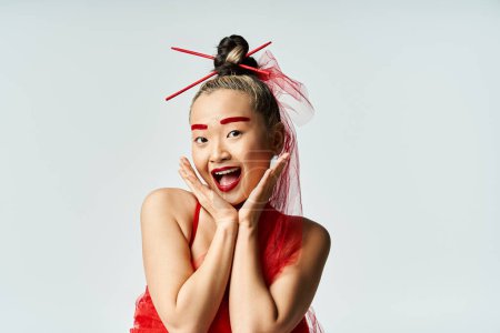 Foto de Mujer asiática en vestido rojo con las manos en la cara. - Imagen libre de derechos