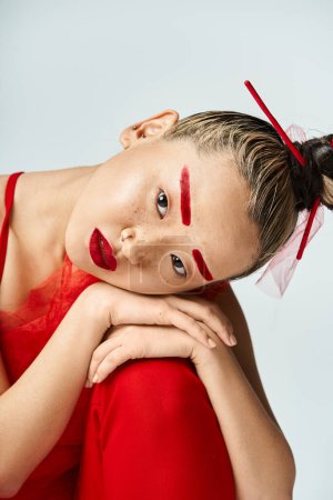 Femme asiatique en robe rouge et rouge à lèvres frappant une pose.