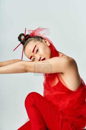 Téléchargez les photos : Une femme asiatique attrayante dans une robe rouge vibrante posant avec confiance pour une image. - en image libre de droit