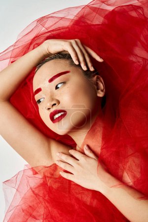 Asian woman in red dress poses with hands on head.