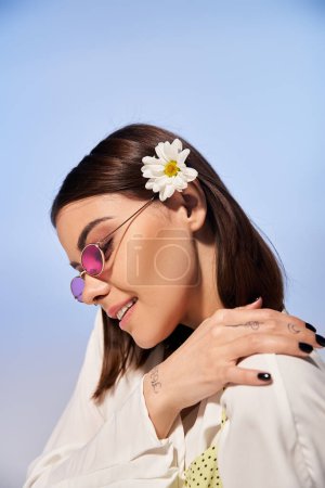 A young woman with brunette hair adorned with a flower, exuding natural beauty and femininity.