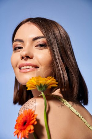 A young woman with brunette hair holding a delicate flower, exuding grace and elegance.