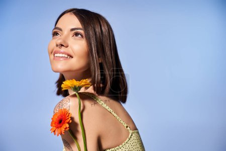 Eine junge Frau mit brünetten Haaren hält eine zarte Blume in der Hand, die Anmut und natürliche Schönheit ausstrahlt.