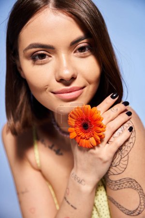 Foto de Una joven con el pelo moreno sosteniendo una flor vibrante en su mano, mostrando belleza natural y gracia. - Imagen libre de derechos