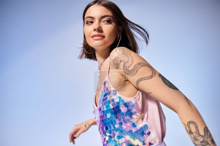 A young brunette woman showcasing a tattoo on her arm in a stylish studio setting.