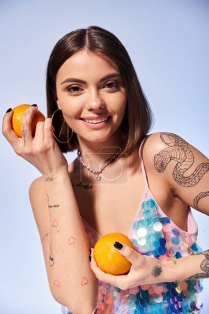 A young woman with brunette hair holding an orange in one hand and a slice of fruit in the other.
